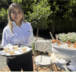 Hostly server offering rosé wine at a private outdoor event in Miami